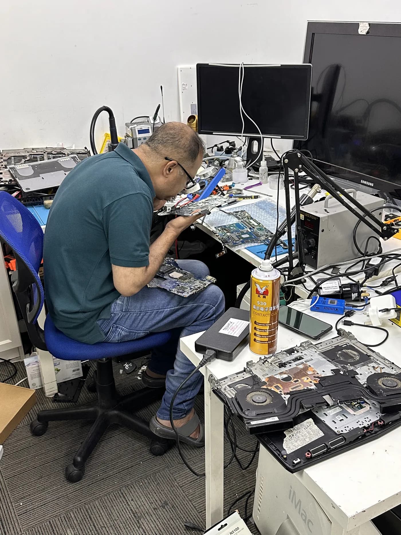 TechFix engineer working at the repair bench with a microscope
